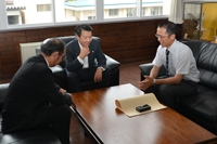 長谷部北秋田地域振興局長から叙勲の伝達を受ける春日朋一さん （7月11日、市役所）2